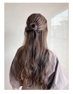 Detail view of a brown bird nest hair clip securing a bun on a woman's long hair