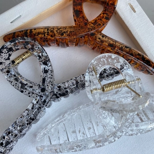 Detail of three large marble and ink pattern hair claws with strong metal springs