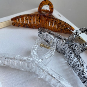 Detailed top view of three large geometric hair claws in amber and marble patterns