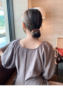 Detail of amber bird nest hair clip securing a low bun hairstyle in a cafe setting
