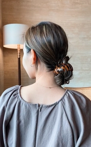 French retro amber tortoise hair claw securing a bun on a woman's hair in a home setting