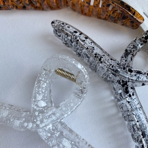 Detailed close-up of large ink-patterned hair claws featuring premium metal springs