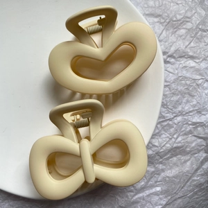 Minimalist matte cream hair claws set with heart and bow cutouts on elegant tray