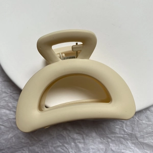 Close-up of matte beige geometric hair claw clip with internal metal spring mechanism