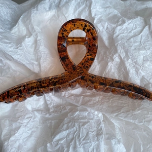 Detailed view of large amber leopard print hair claw clip with golden metal spring