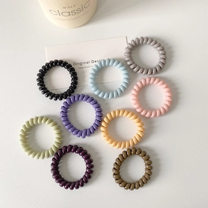 Set of 9 colorful spiral hair ties in pastel shades on a minimalist white background