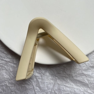 Macro view of a matte cream geometric hair claw clip on a white decorative paper background