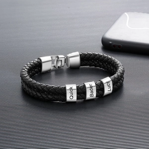 Detailaufnahme von geflochtenem Lederarmband mit individuell gravierten Metallperlen auf grau