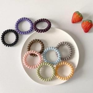 Set of pastel spiral telephone cord hair ties in various colors on white porcelain plate