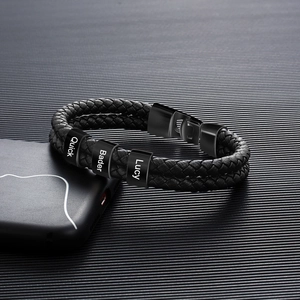 Detail eines geflochtenen Lederarmbands mit drei individuell gravierten Namensringen