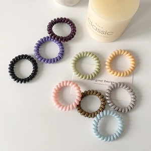 Flat lay of colorful spiral telephone wire hair ties with pastel colors on white background