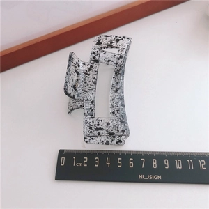 Detail view of large ink pattern hair claw clip next to a ruler for 8cm size reference