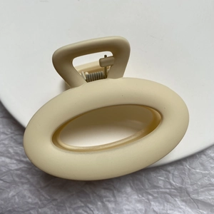 Close-up of matte cream geometric hair claw clip with silver metal spring component