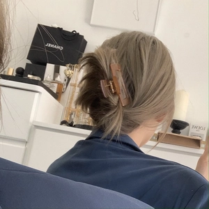 Close-up of a translucent amber resin rectangular hair claw clip in a messy bun hairstyle