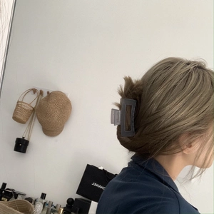 Detail view of a large grey matte square hair claw clip styled on a model in a home setting