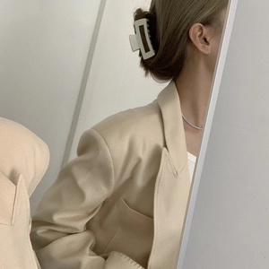 Detail of matte cream rectangular hair claw clip and silver gemstone necklace on model