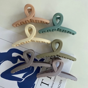 Detail of six matte Morandi colored 12cm hair claws with a cross-knot design and multi-teeth