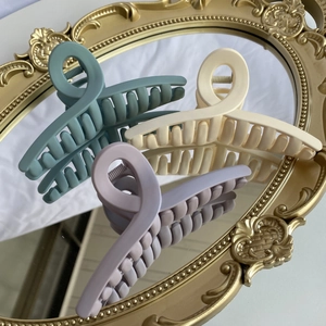 Three large matte claw clips in morandi green cream and lilac on a decorative mirror