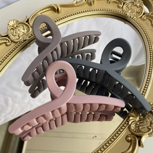 Detail of 12cm matte hair claw clips in muted pink and grey on a vintage gold mirror