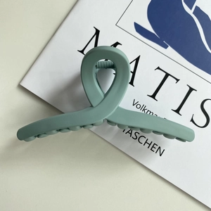 Macro view of matte sage green hair claw clip with minimalist twisted crossover design