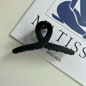 Close-up of a matte black hair claw clip with a stylish cross-ribbon design