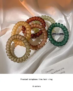 Détail d'élastiques à cheveux spirales mats de 5,5 cm sur tissu en soie élégant