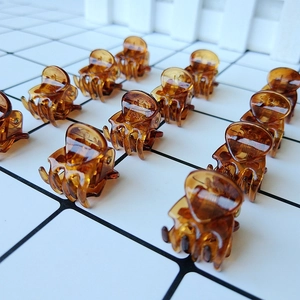 Close-up of 12 mini amber hair claws arranged on a grid background for hairstyling