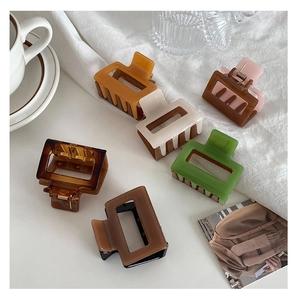 Close-up of stylish 5cm square hair claws in amber, beige and green tones on a desk