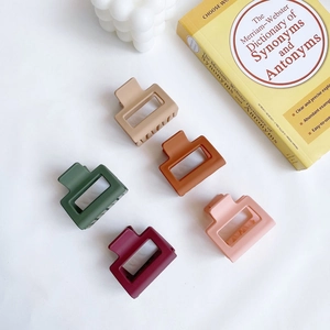 Five matte rectangular hair claws in Morandi colors shown with aesthetic props