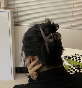 Deep brown matte hair claw clip with geometric cross design shown on hair back