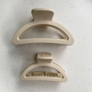 Detail view of two matte cream hair claws in different sizes for versatile styling
