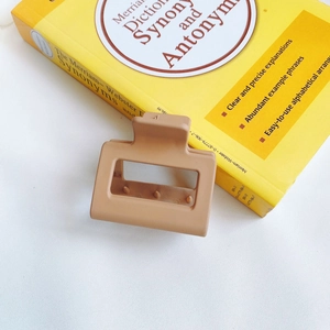 Detail shot of a rectangular matte claw clip in milk tea color on a book background