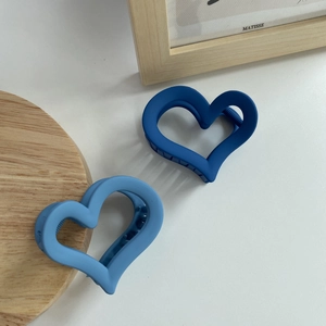 Matte heart hair claws in navy and light blue displayed on a minimalist white surface