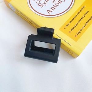 Close-up of black matte rectangular hair claw clip placed on a yellow dictionary