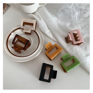 Detail showing set of six colorful square hair claws scattered on a white table