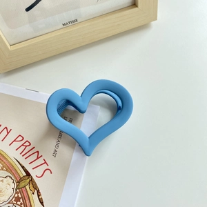 Close-up of sky blue heart-shaped hair claw clip with a matte frosted finish texture