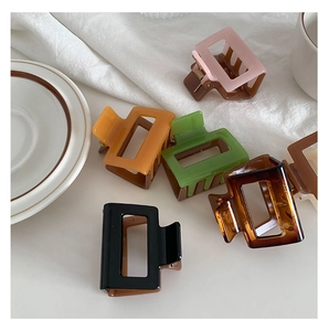Detailed view of colorful square resin hair claws on a white linen fabric background