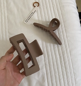 Detail of matte rectangular and cross-twist hair claws in soft Morandi coffee tones