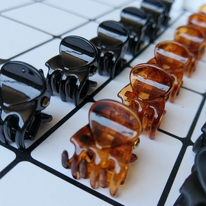 Minimalist 1.5cm mini hair claws in black and amber resin neatly arranged on a grid
