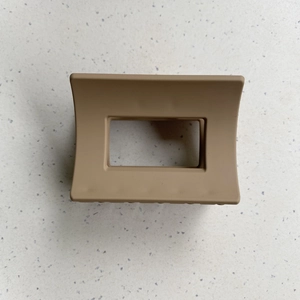 Macro detail of a large matte khaki rectangular hair claw clip for elegant styling