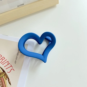 Detail view of the large Klein Blue matte heart-shaped hair claw clip on a minimalist surface