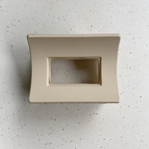 Top view of a large matte beige rectangular hair claw clip on a terrazzo surface