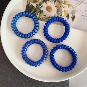 Gros plan de quatre élastiques spirale bleu foncé aux finitions mates et brillantes sur plat