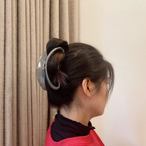 Detailed back view of a large translucent grey hair claw clip styling a woman's hair