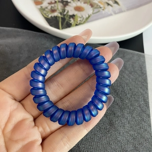 Gros plan d'un élastique spirale bleu Klein mat avec des reflets violets nacrés