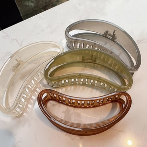 Set of four large crescent claw clips in jelly colors on marble surface