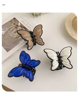 Three butterfly hair claws in khaki, blue, and cream white displayed on a white surface