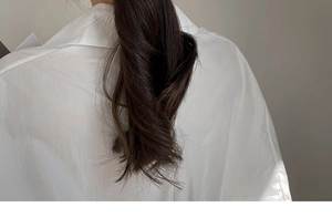 Close-up of deep brown wavy ponytail hair extension with smooth matte finish clip