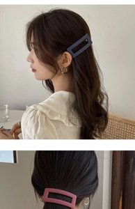 Detail of navy blue and rose pink matte rectangular hair clips in a cafe setting