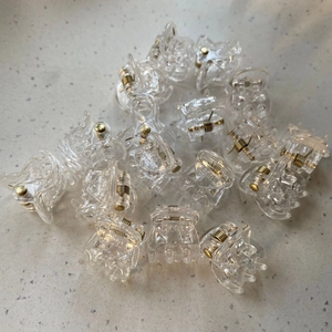 Macro shot of transparent mini hair claws with golden metal springs in a bulk pack